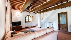 A living room with a sofa, a TV, and a staircase. - Villa Vittoriano - Surrounded By Nature (Camaiore)