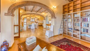 Un salón amplio con suelo de madera, una gran estantería y un tapete rojo con estampado.