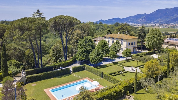 Un grand jardin bien entretenu, doté d’une piscine, et bordé de haies et d’arbres taillés avec soin.