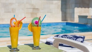 Two tall glasses of orange juice with straws and garnishes by a poolside. - Holiday home Škrika -Three Bedroom Home with heated Pool and Jacuzzi (Skrip)