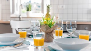 A breakfast setting with a table set for two, including plates, glasses, and a vase with flowers. - Holiday home Škrika -Three Bedroom Home with heated Pool and Jacuzzi (Skrip)