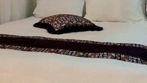 A bed with a tufted headboard, white bedding, and a patterned throw. - Hotel Judith (Gulu)