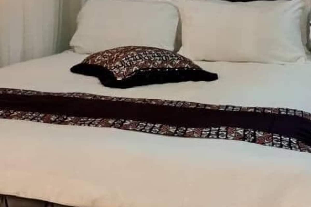 A bed with a tufted headboard, white bedding, and a patterned throw.