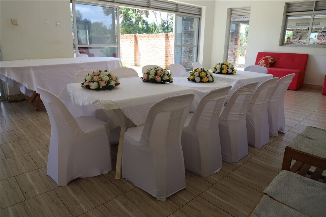Un'area pranzo con tavoli e sedie bianche, ognuno decorato con un centrotavola floreale.