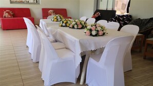 A dining area with a long table covered in white tablecloths, surrounded by white chairs. - Hotel Judith (Gulu)