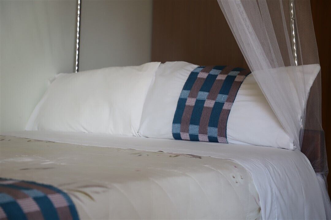 A bed with white bedding and a striped pillow.