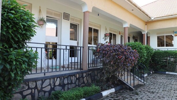 A building with a stone facade, a covered porch with a railing, and a cobblestone courtyard. - Hotel Judith (Gulu)
