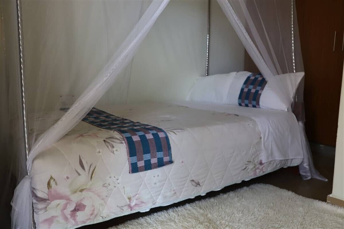 A bed with a canopy, a floral bedspread, and a checkered throw.