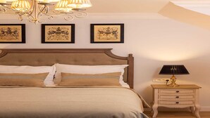 Un dormitorio con una cama grande, una mesita de noche con una lámpara y tres cuadros en la pared.