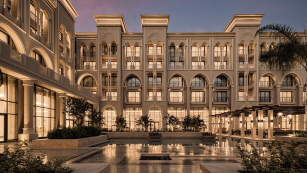 Een groot hotel met meerdere verdiepingen, een centrale binnenplaats en een zwembad.