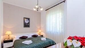 A hotel room with a bed, two bedside lamps, a nightstand, a wooden table, and a vase of flowers.