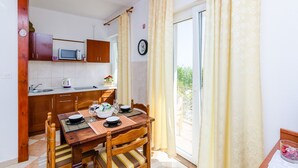 A compact kitchen with wooden cabinets, a microwave, and a dining area with a table set for two.