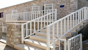 A building with a stone facade, a set of white metal stairs with railings, and a small balcony with a window.