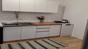A modern kitchen with white cabinets, a stainless steel sink, a coffee maker, and a dishwasher.