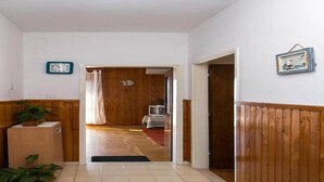 A hallway with wooden paneling, a clock, and a door leading to another room.