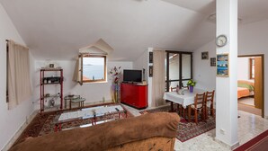 Una sala de estar con sofá, televisor, mesa de comedor y un armario rojo.