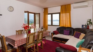 A room with a dining table, chairs, a sofa, and a window with curtains.