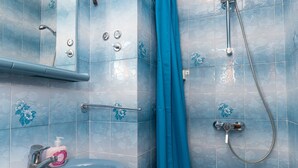 A bathroom with a sink, mirror, shower, and blue tiles.