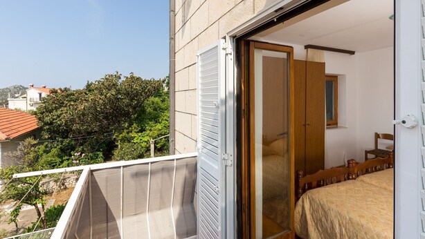 A balcony with a white railing, a wooden bed with a quilted cover, and a wooden wardrobe.