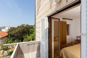 A balcony with a white railing, a wooden bed with a quilted cover, and a wooden wardrobe.