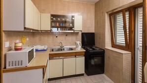 A compact kitchen with a microwave, stove, sink, and cabinets.
