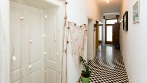 Een gang met een geruit vloerkleed, een groene plant en een reeks decoratieve objecten.