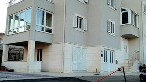 Un edificio residencial de varios pisos con fachada plana, ventanas grandes y entrada protegida por una reja.