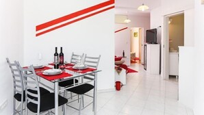 Un comedor moderno con una mesa de vidrio, sillas de metal y detalles en rojo.