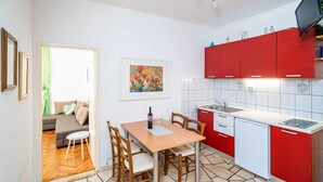Una cocina compacta con armarios rojos, una encimera blanca y un pequeño comedor con mesa y sillas.