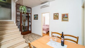 Un comedor con una mesa lista para dos personas, una botella de vino y dos copas de vino.