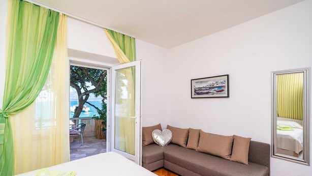 Una habitación con un sofá, un cojín con forma de corazón, un cuadro enmarcado y vistas al exterior.