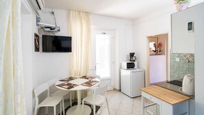 A compact kitchen with a dining area, a flat-screen TV, a microwave, and a refrigerator.