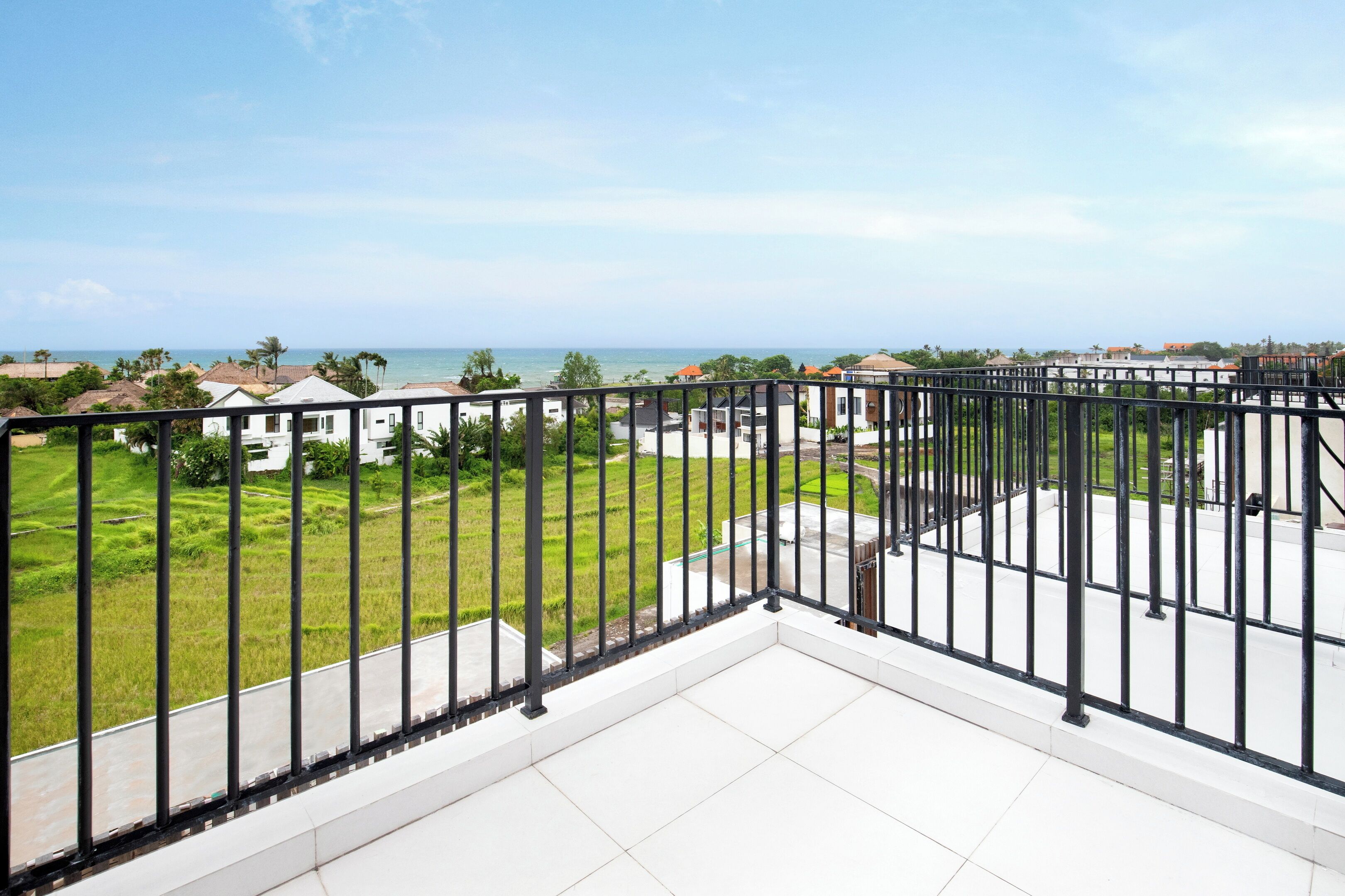 A balcony with a view of a residential area and the sea.