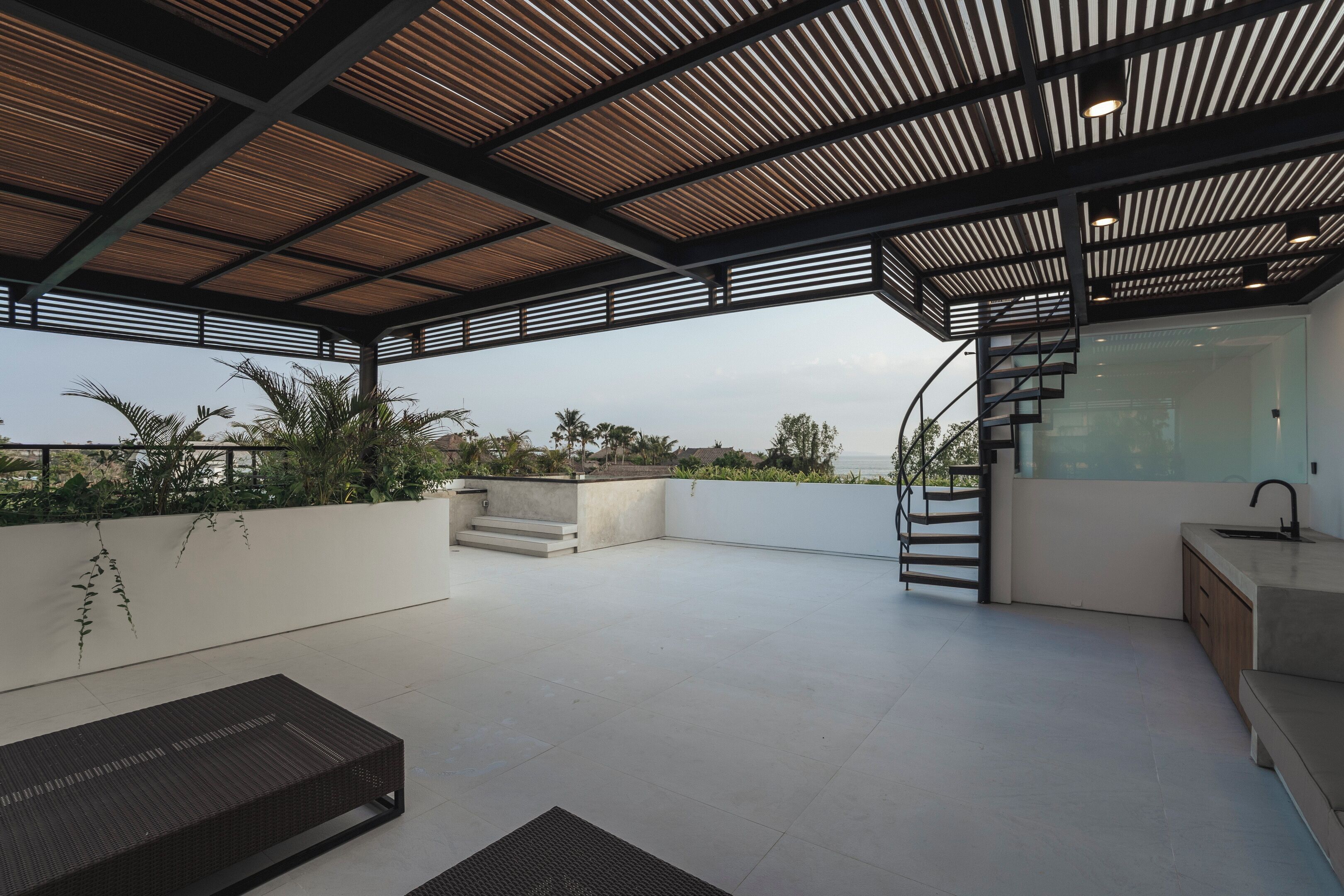 Una terraza moderna en la azotea con una pérgola de madera, cocina integrada y una escalera en espiral.