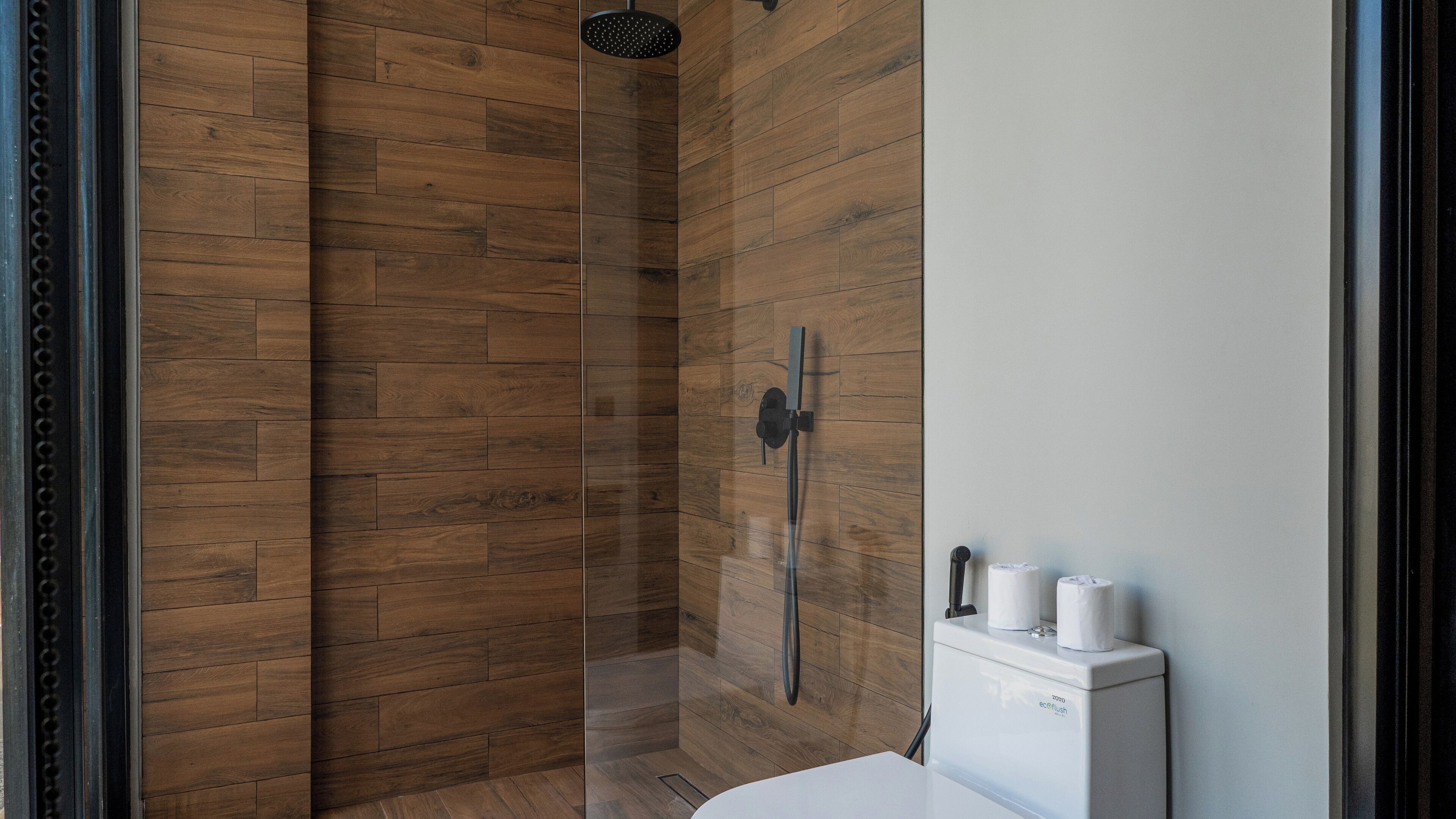 Une salle de bain moderne avec un lambris en bois, une douche en verre et un lavabo blanc avec des toilettes.