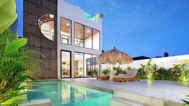A modern two-story house with a swimming pool, outdoor seating, and lush greenery. - Aquamarine Villas III (Munggu)