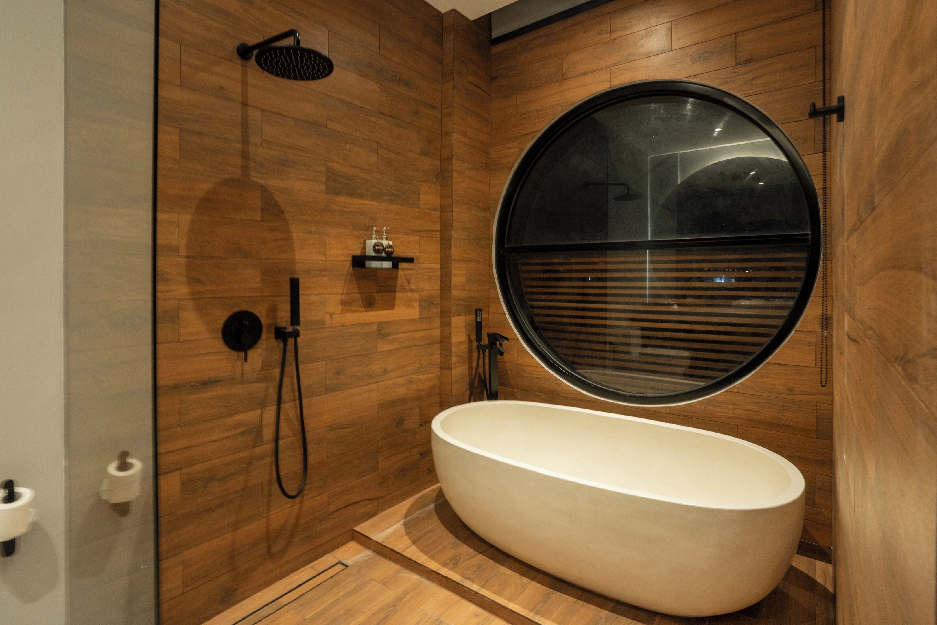 Ein modernes Badezimmer mit einer freistehenden Badewanne, einer Dusche und einem großen Fenster.