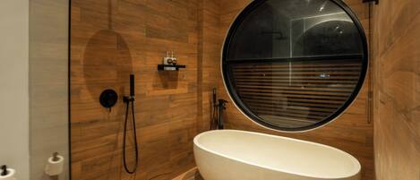 Ein modernes Badezimmer mit einer freistehenden Badewanne, einer Dusche und einem großen Fenster.