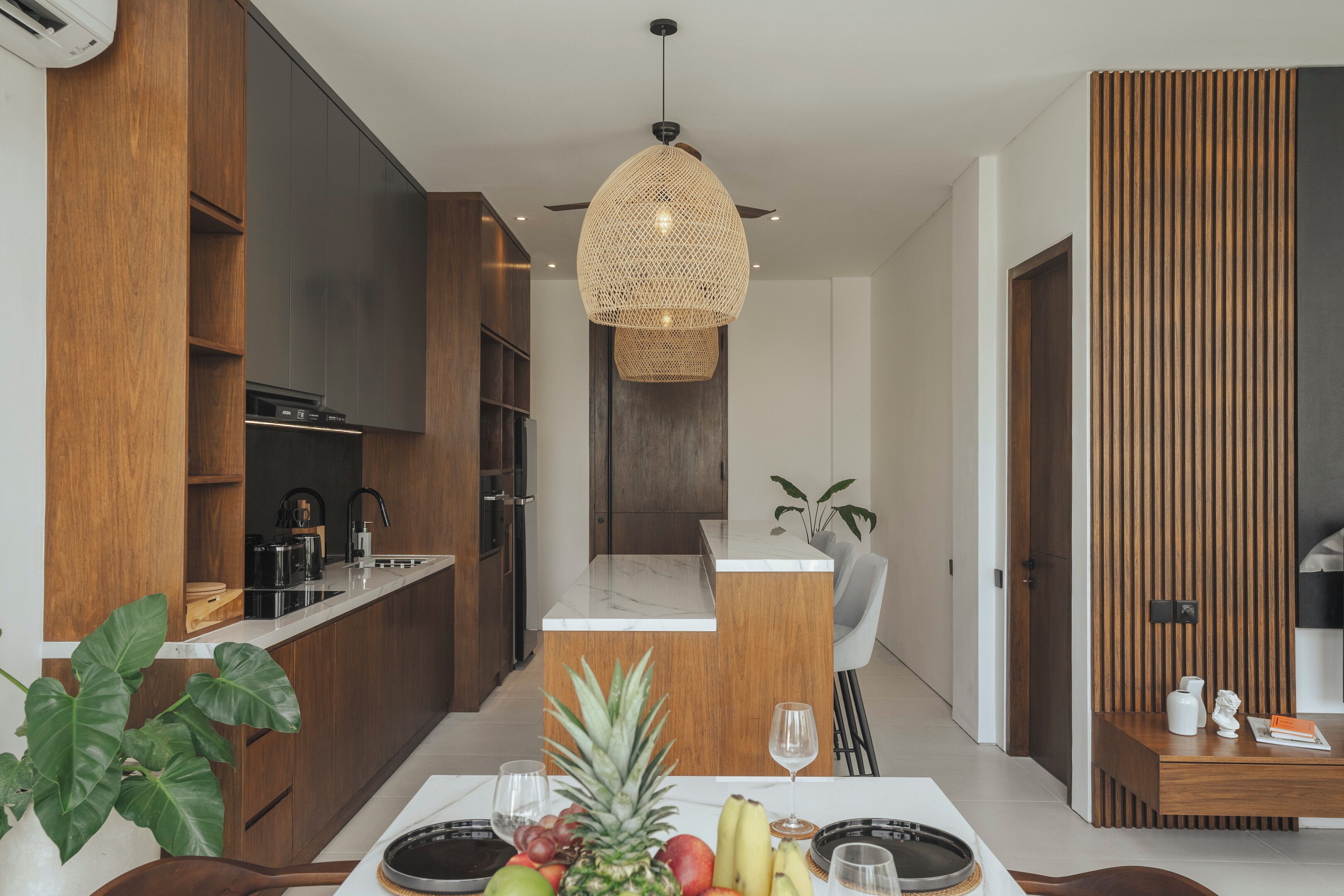Une cuisine moderne avec un îlot central, des meubles en bois et un luminaire suspendu.
