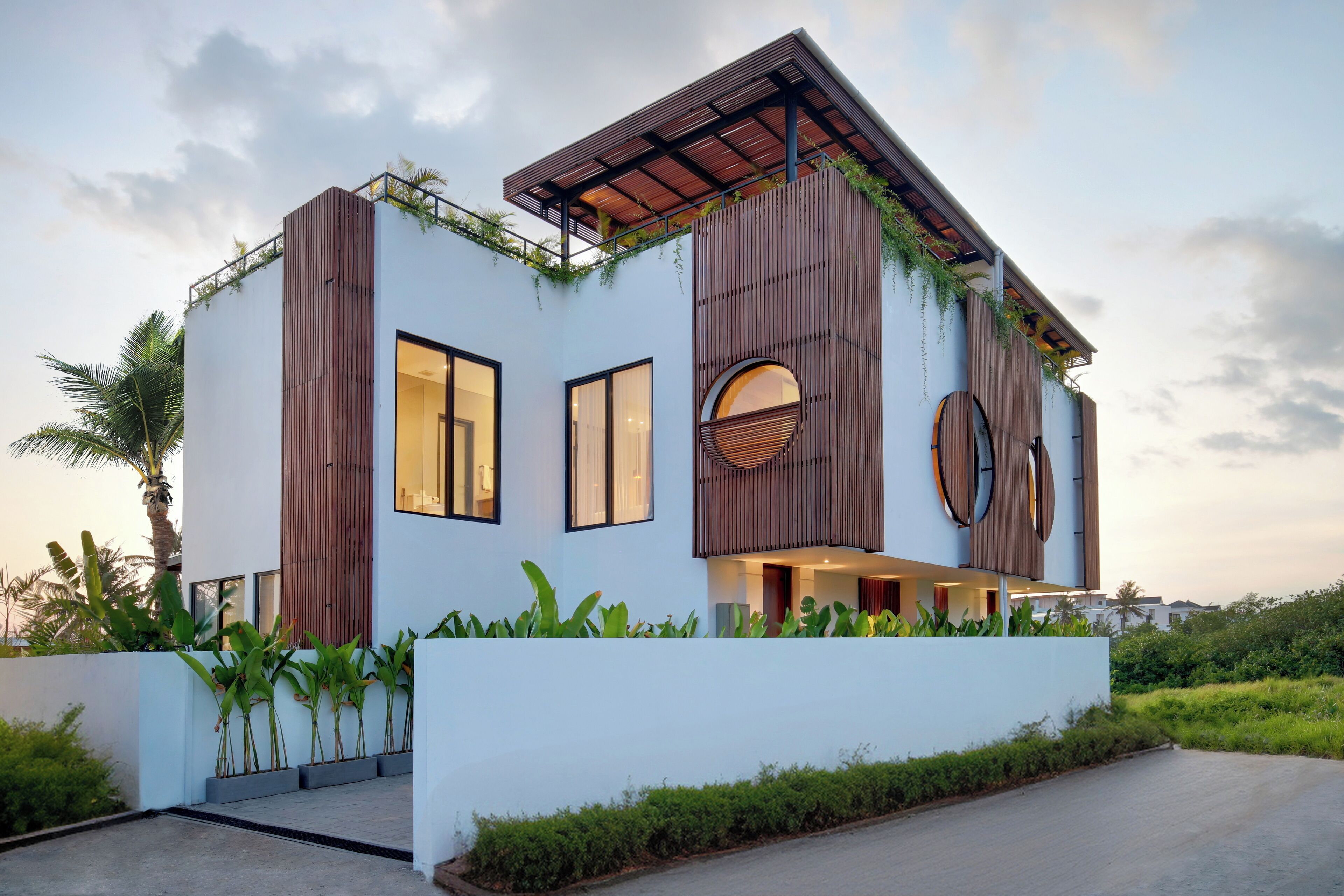 Una casa moderna de dos pisos con techo plano, ventanas grandes y un tragaluz circular.