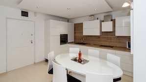 Una cocina moderna con armarios blancos, una pared de acento de madera y una mesa de comedor redonda con sillas.