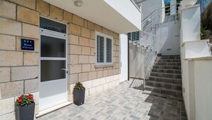 A building with a stone facade, a glass door, and a staircase leading to an upper level.