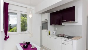 A modern kitchen with white cabinets, a built-in oven, and a stainless steel sink. - Apartments Posta - One-Bedroom Apartment with Terrace and Sea View - Apartman 5 (Saplunara)