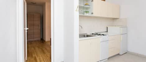 A modern kitchen with white cabinets, a built-in oven, and a refrigerator.