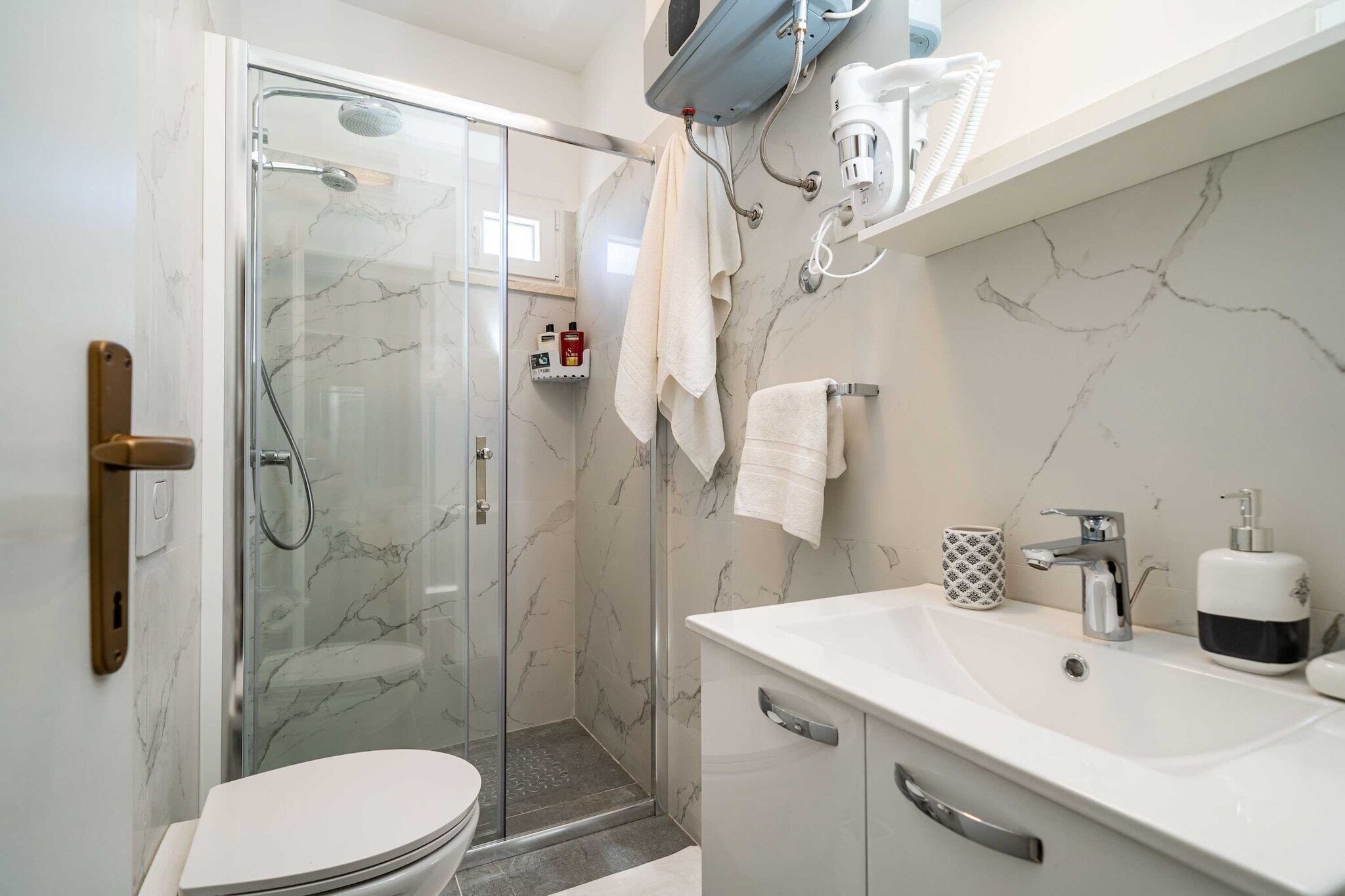 A modern bathroom with a glass-enclosed shower, a white sink, and a toilet.