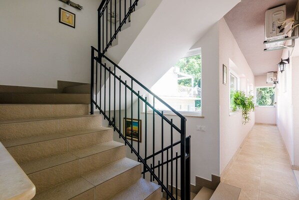 A staircase with beige steps and black railings, leading to a landing with a framed picture.