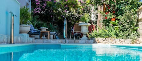 En swimmingpool med stenvæg og plantekasser.