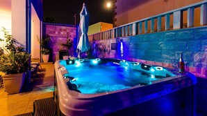 A hot tub with multiple jets, surrounded by potted plants and a stone wall.
