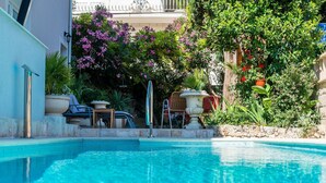 Una piscina con pared de piedra y plantas en macetas.