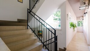 Una escalera con escalones color beige y barandillas negras, que conduce a un rellano con un cuadro enmarcado.